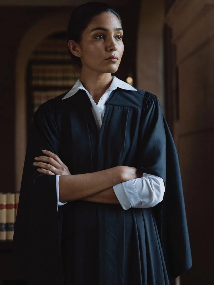 A woman lawyer in a black robe standing in a wood-panelled chamber
