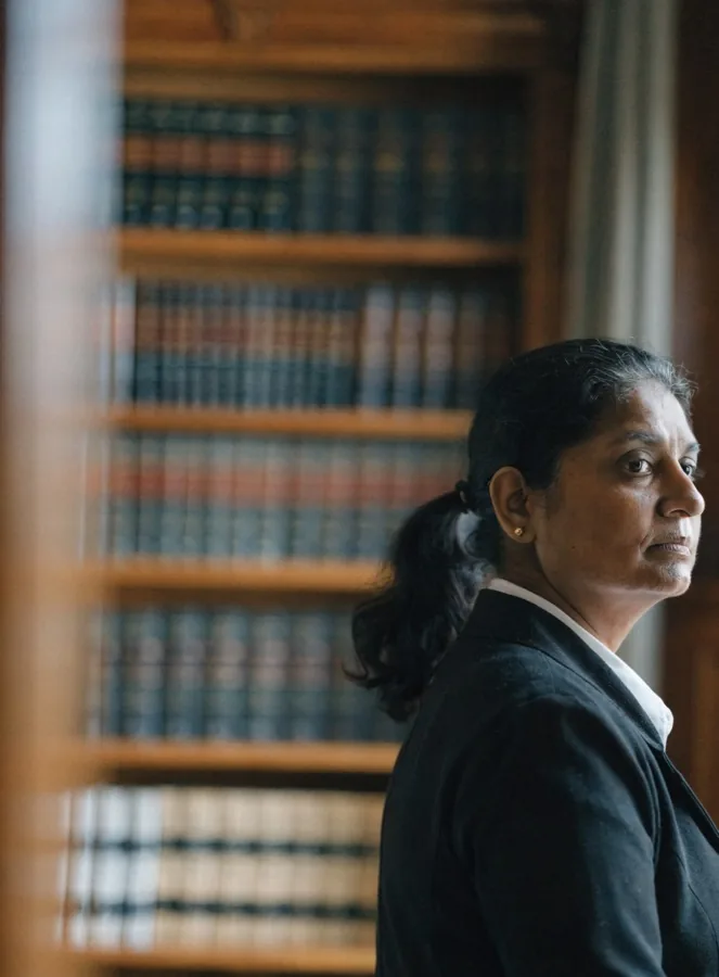 A thoughtful woman in a dark jacket standing in a library