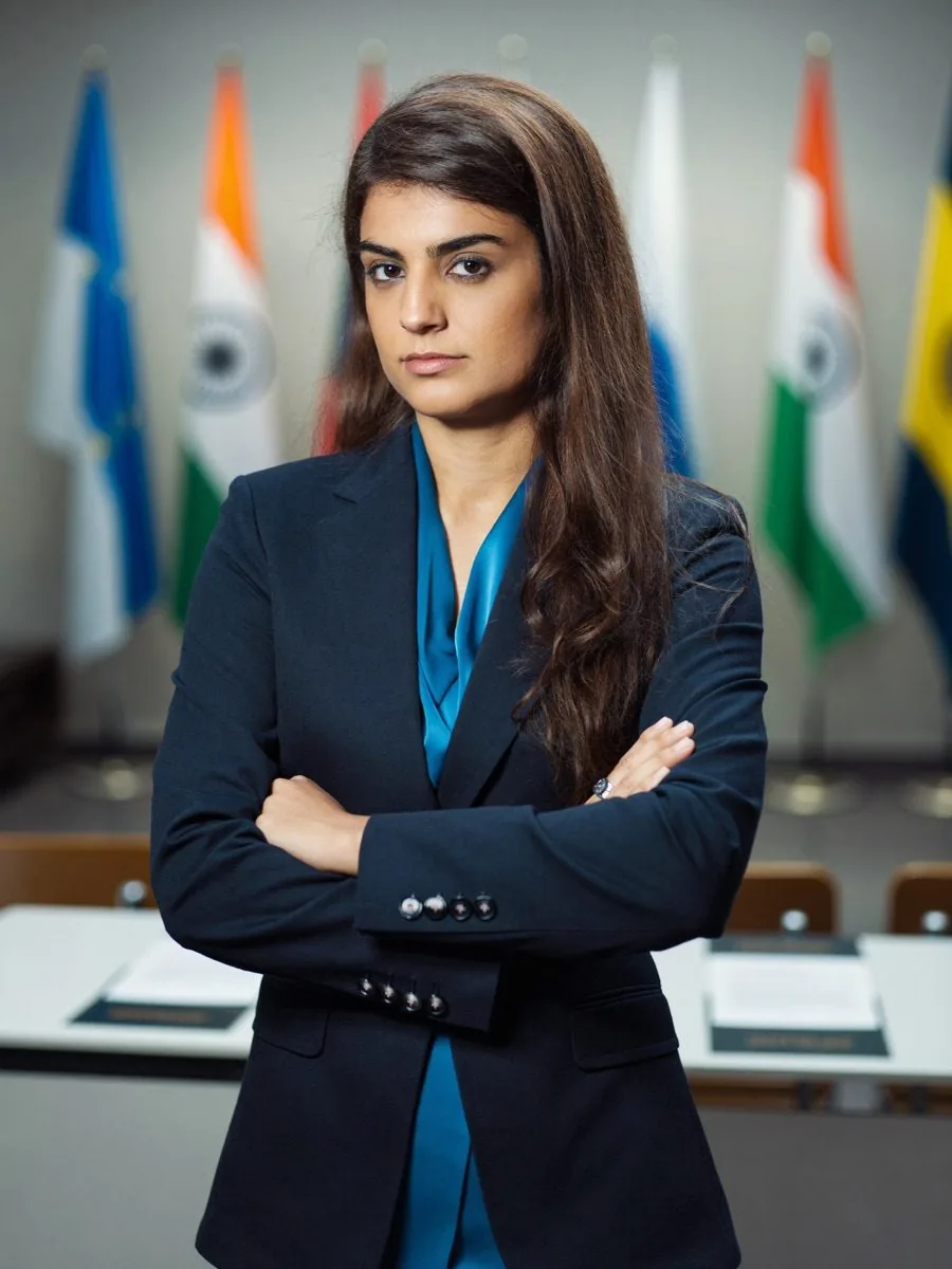 A woman diplomat with arms folded in front of national flags